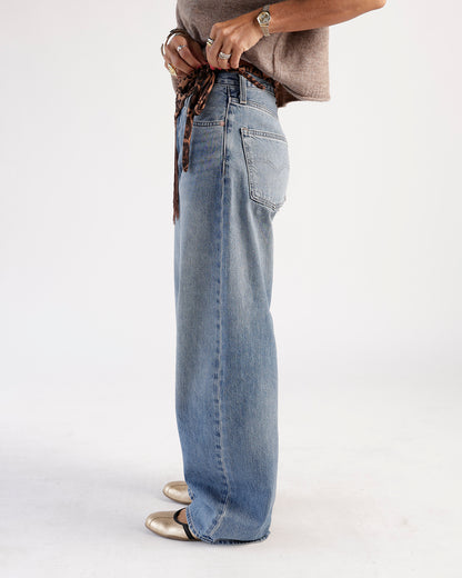Side view of wide-leg medium wash blue jeans with back pocket and leopard belt