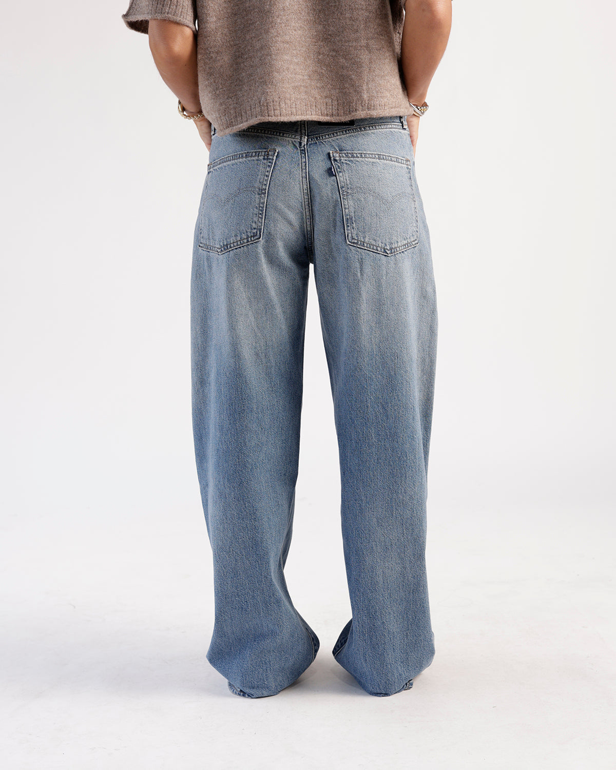 Back view of medium wash blue loose-fit jeans with two back pockets