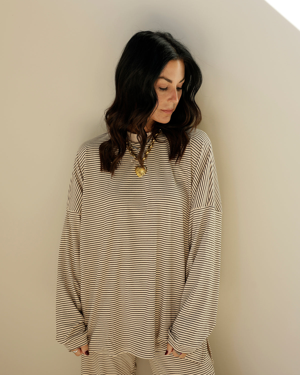 woman wearing an oversized cream and black micro-striped long sleeve top by things between with dropped shoulders and a relaxed fit.