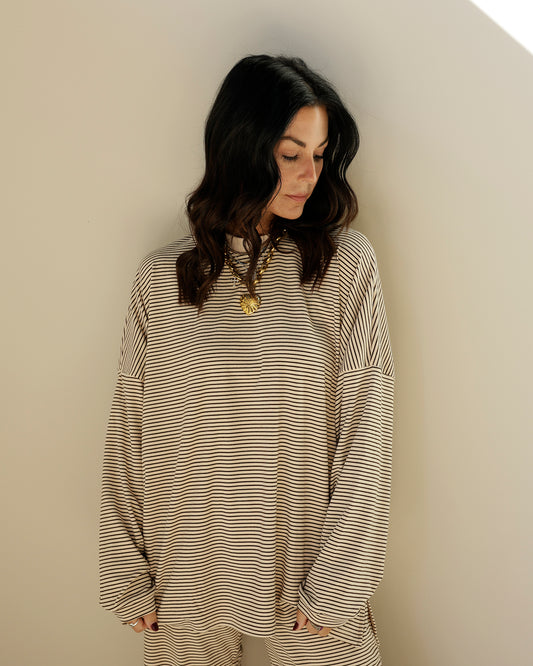 woman wearing an oversized cream and black micro-striped long sleeve top by things between with dropped shoulders and a relaxed fit.