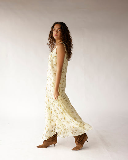 Cream floral maxi dress with thin straps and flowy skirt, styled with brown boots.