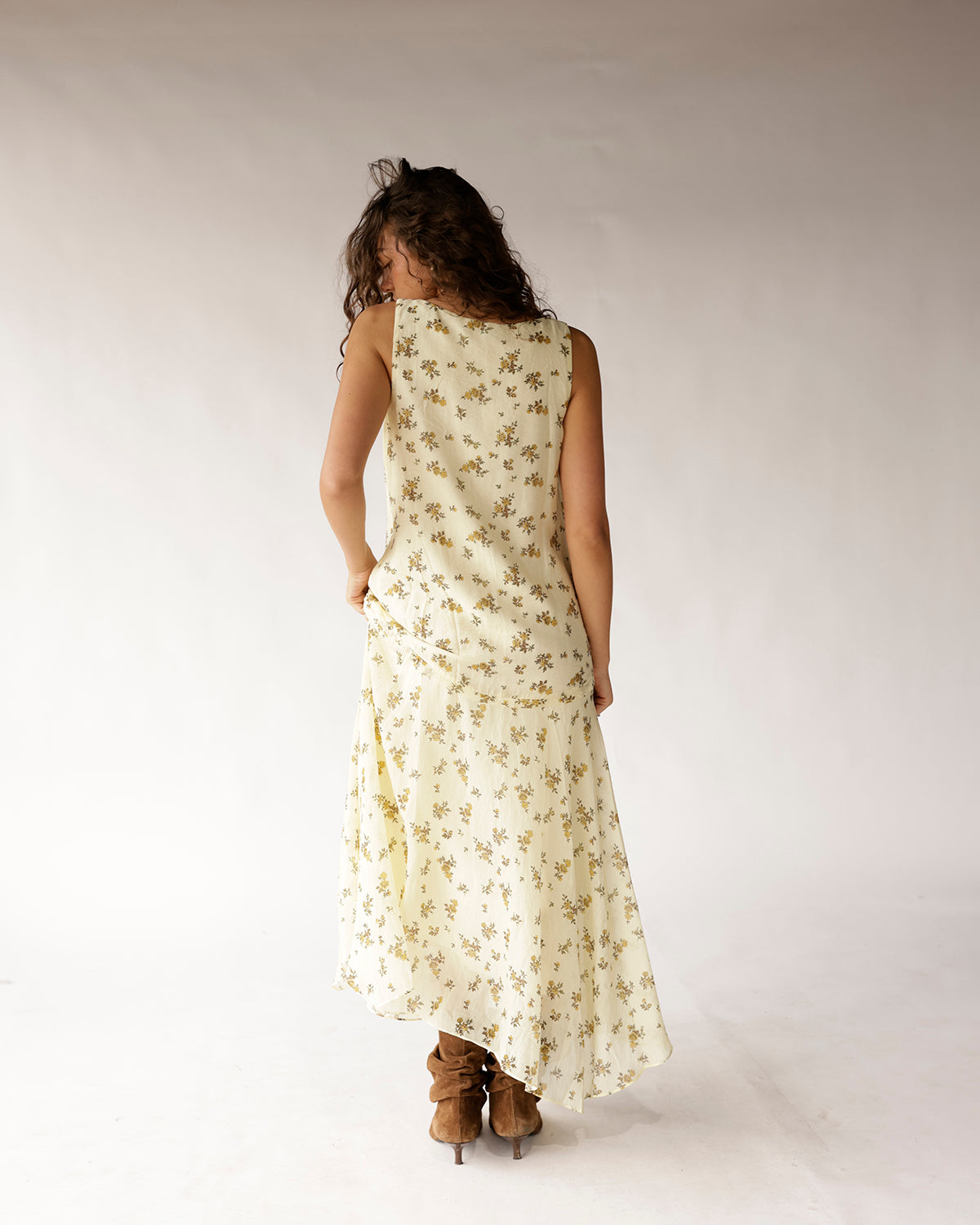 Cream sleeveless floral maxi dress with asymmetric hem, worn with brown heeled boots