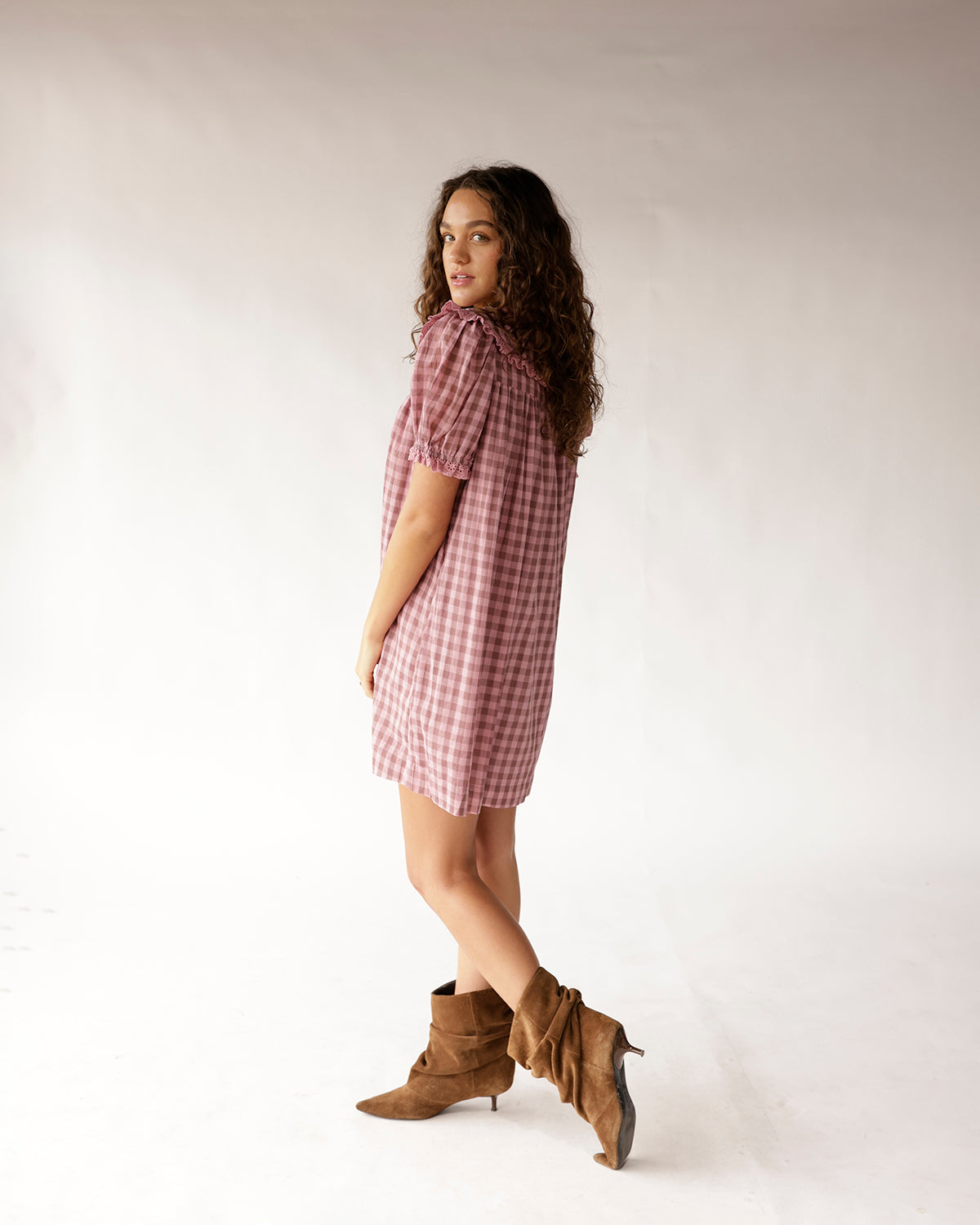 Pink gingham mini dress with puff sleeves and ruffle collar, paired with tan suede boots