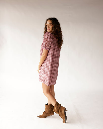 Pink gingham mini dress with puff sleeves and ruffle collar, paired with tan suede boots