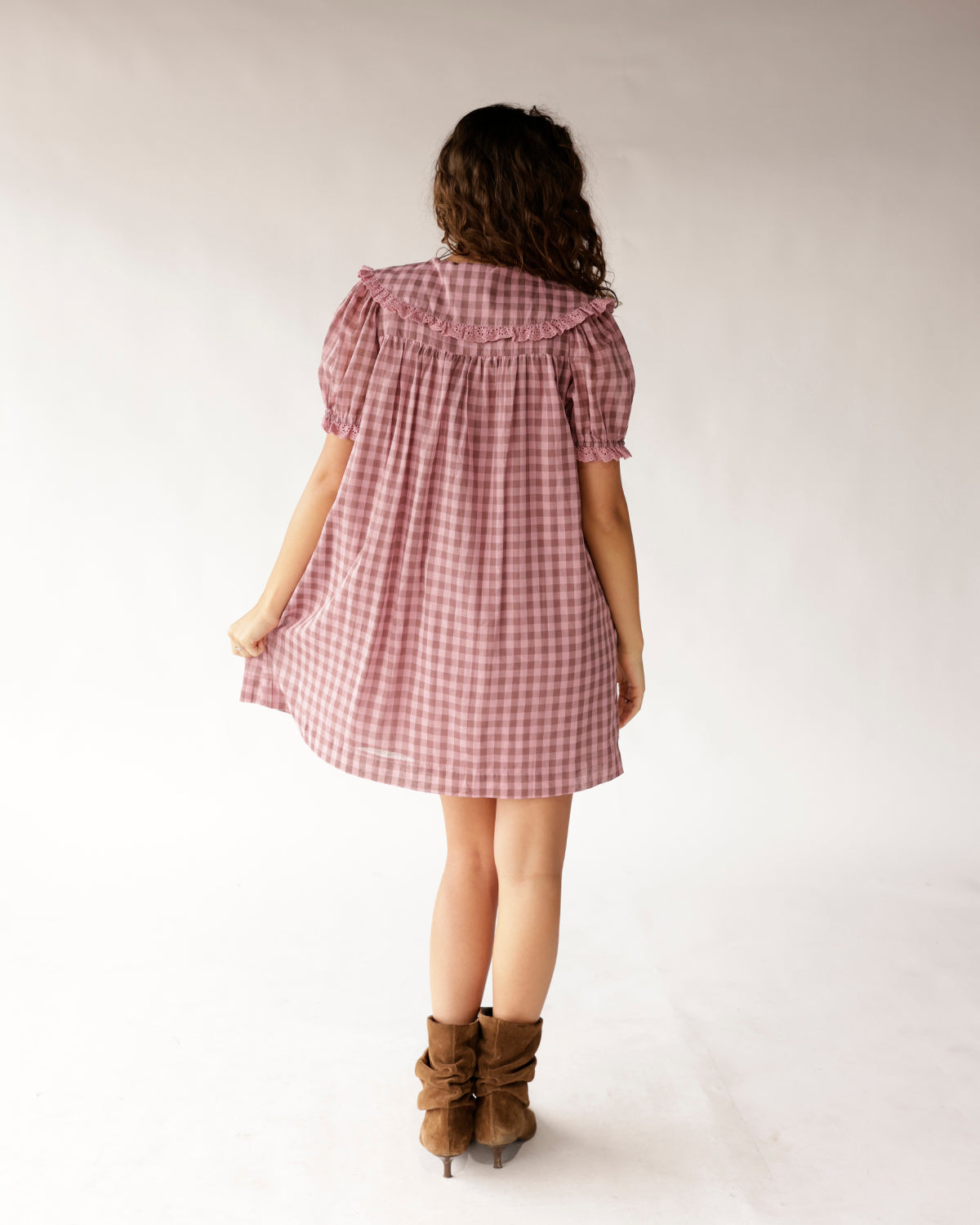 Pink gingham mini dress with ruffle collar, puff sleeves, and brown ankle boots