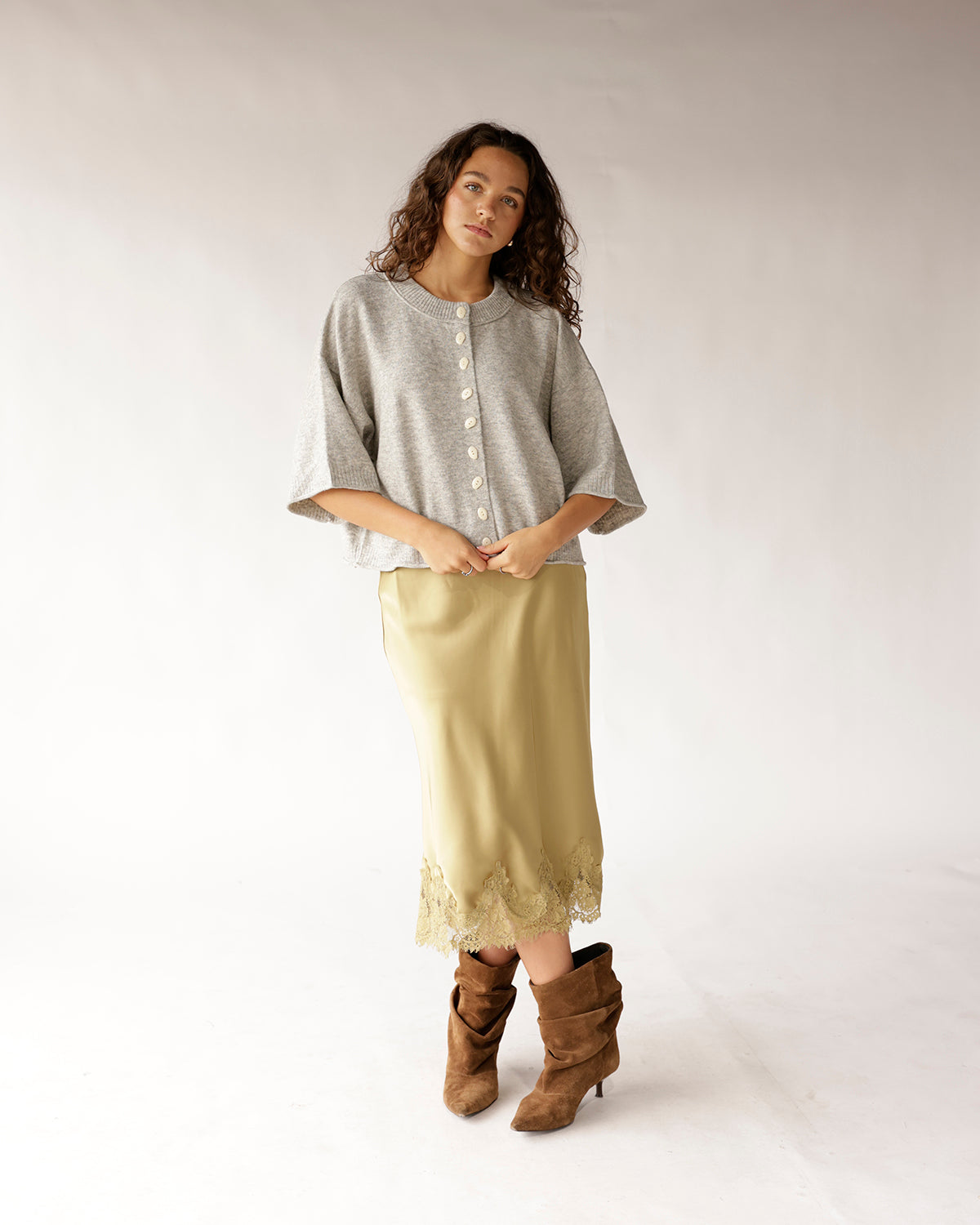 Cropped gray knit cardigan with white buttons and wide three-quarter sleeves