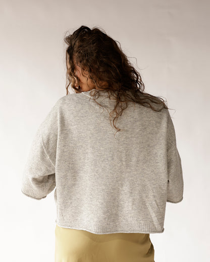 Light gray cropped knit sweater with ribbed hem, shown from the back