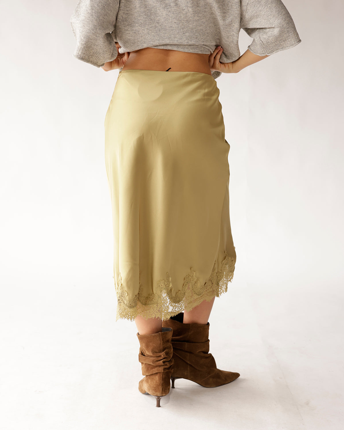 Olive green satin midi skirt with lace hem trim, styled with brown suede boots