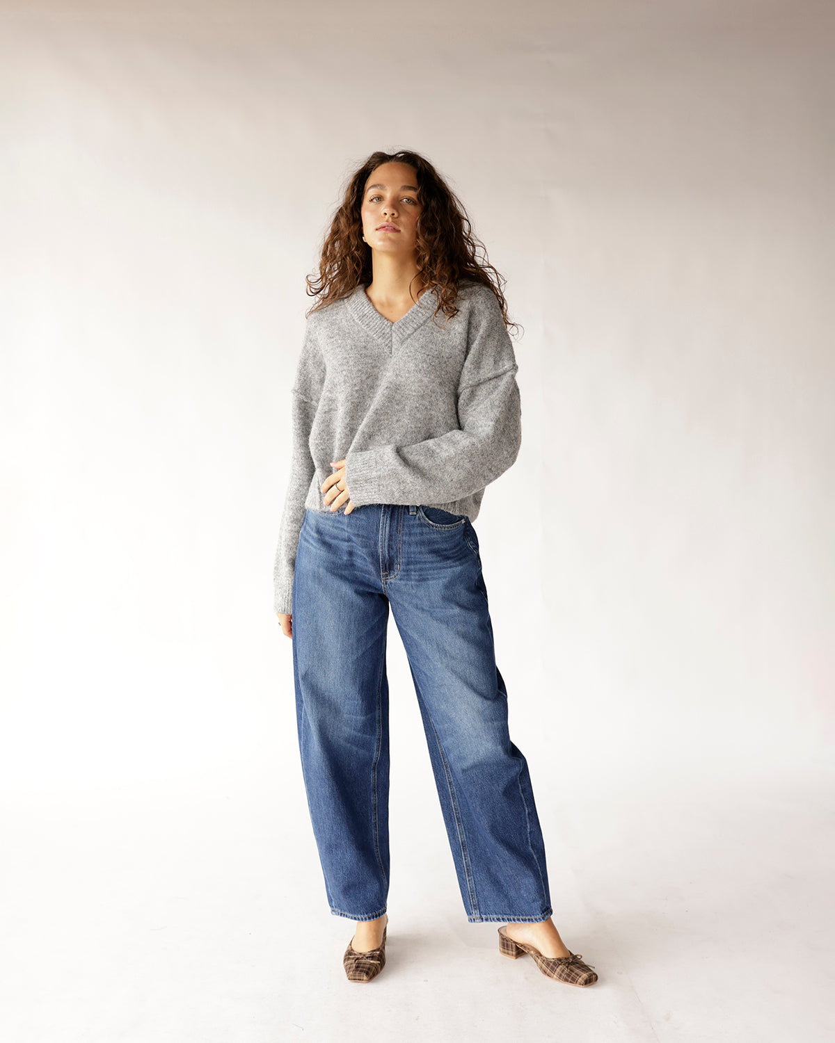 Oversized gray V-neck knit sweater styled with wide-leg blue jeans