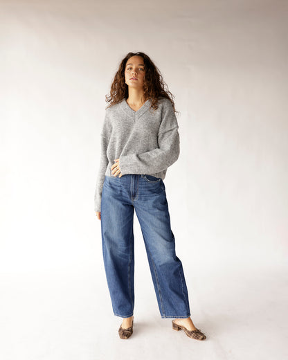 Oversized gray V-neck knit sweater styled with wide-leg blue jeans