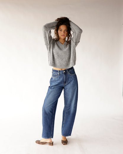 High rise relaxed barrel leg blue jeans with raw hem, worn with gray cropped sweater