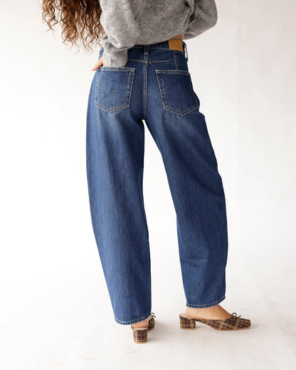 Dark blue high rise relaxed barrel jeans, back view, worn with plaid mules