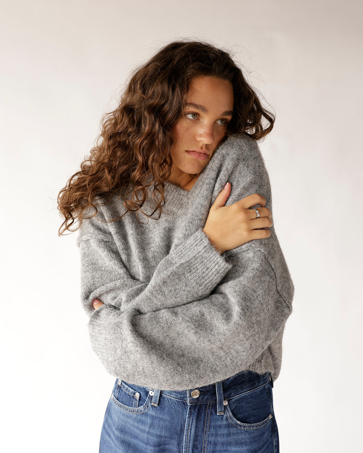 Oversized gray knit V-neck sweater paired with blue high-waist jeans