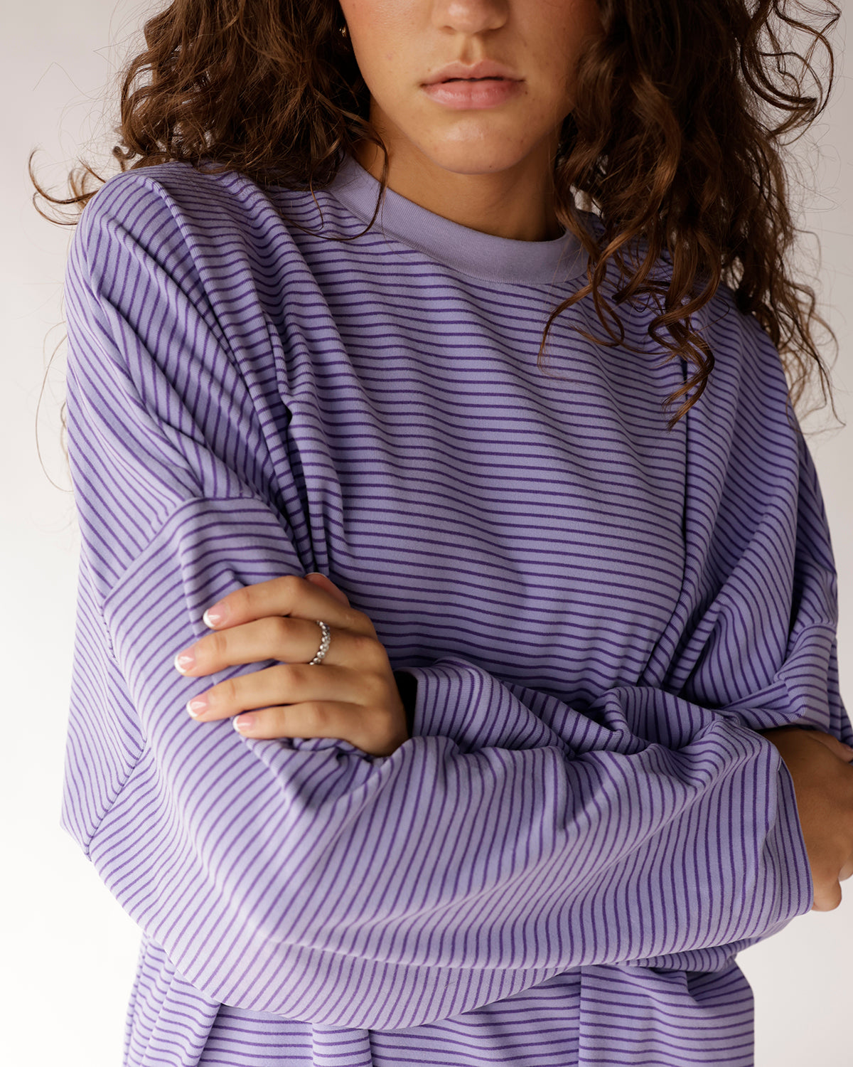 Oversized lavender striped long sleeve top with mock neck, worn crossed-arm