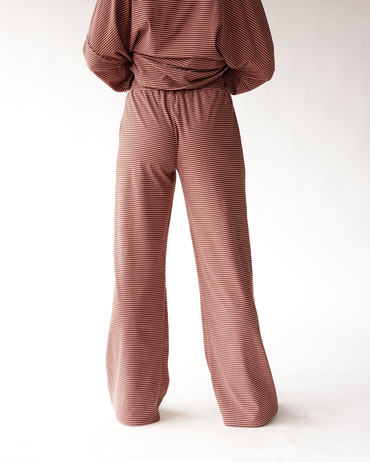 Rust red and white striped wide-leg lounge pants with elastic waistband, back view.