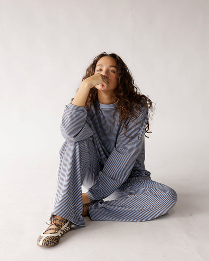 Dusty blue striped long sleeve top with relaxed fit, worn with wide-leg pants