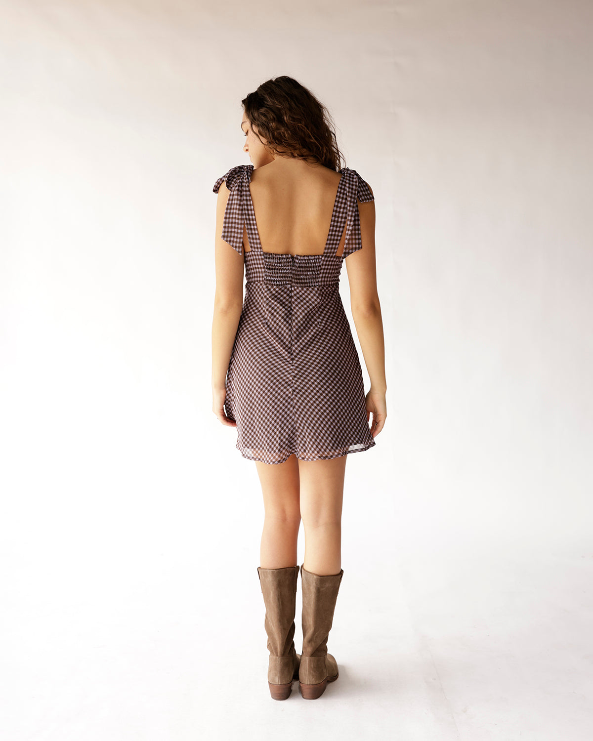 Blackberry gingham mini dress with tie straps, open back, smocked waist, worn with tan boots