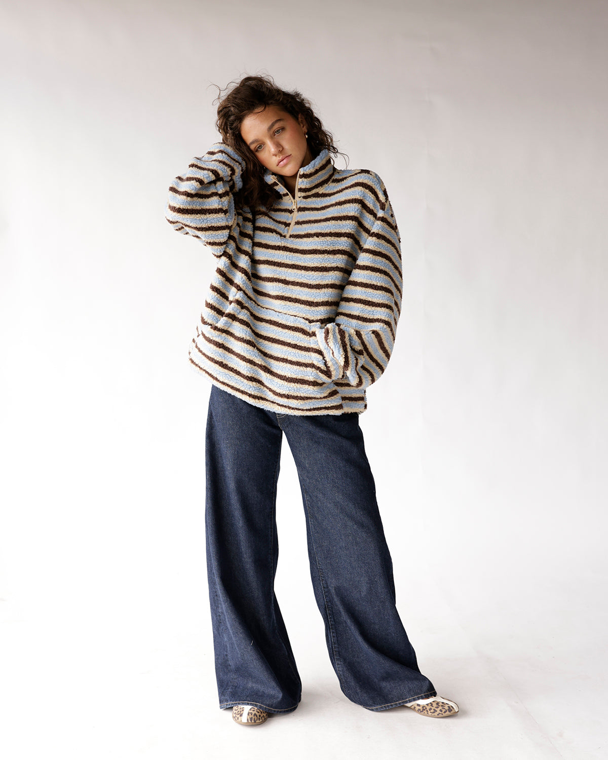 Blue and brown striped sherpa half-zip pullover with wide-leg dark denim jeans