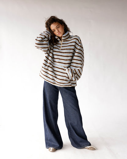 Blue and brown striped sherpa half-zip pullover with wide-leg dark denim jeans