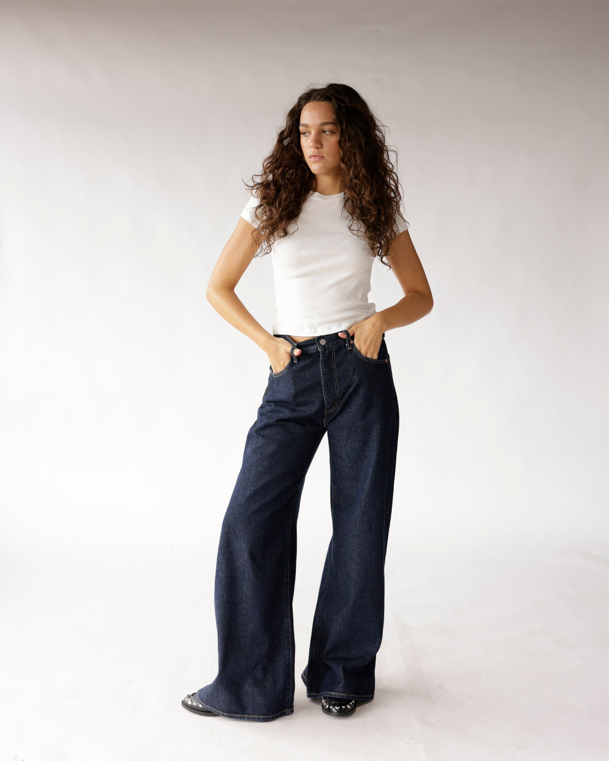 Dark wash wide-leg jeans paired with a white fitted t-shirt and black shoes.