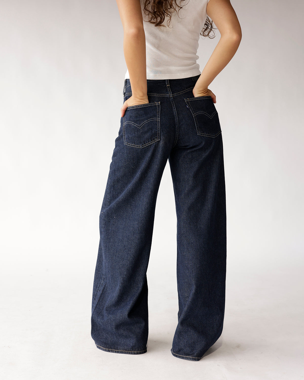Dark wash wide-leg jeans with contrast stitching, back pockets, worn from behind