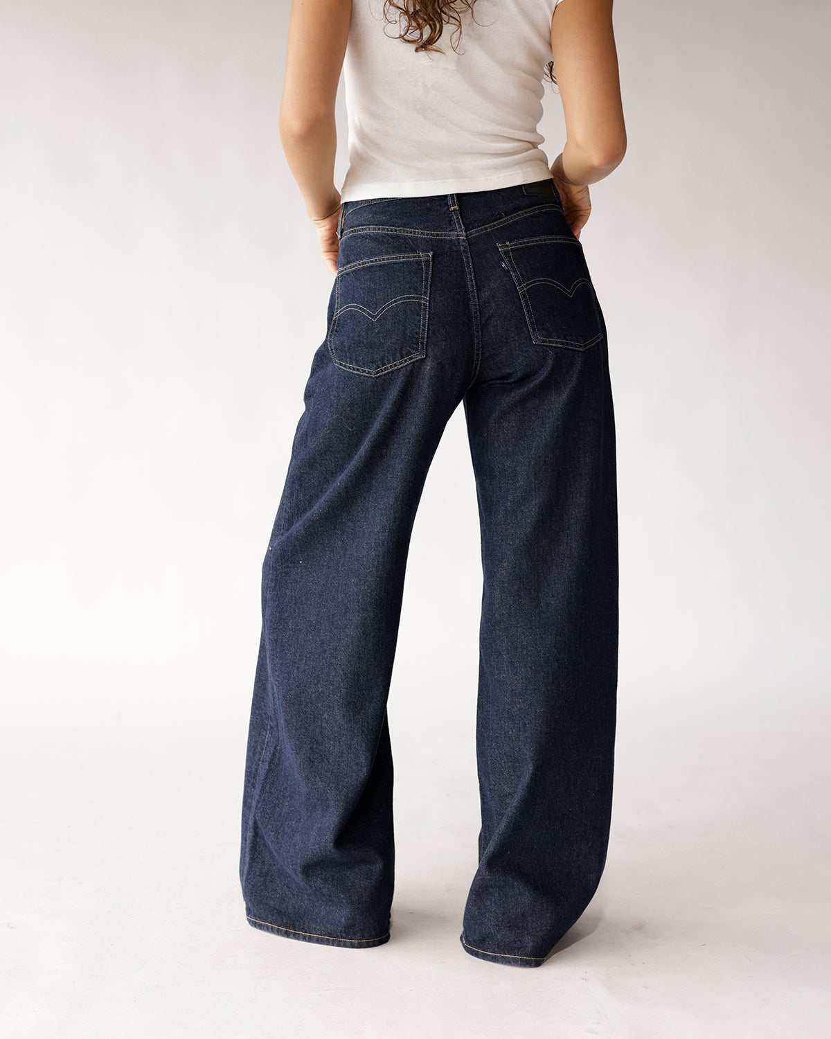Dark wash wide-leg jeans with contrast stitching and back pockets, rear view
