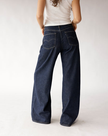 Dark wash wide-leg jeans with contrast stitching and back pockets, rear view