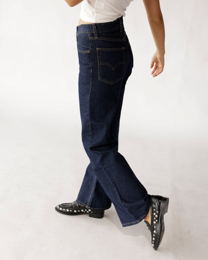 Dark indigo wide-leg boot cut jeans with gold stitching, side view