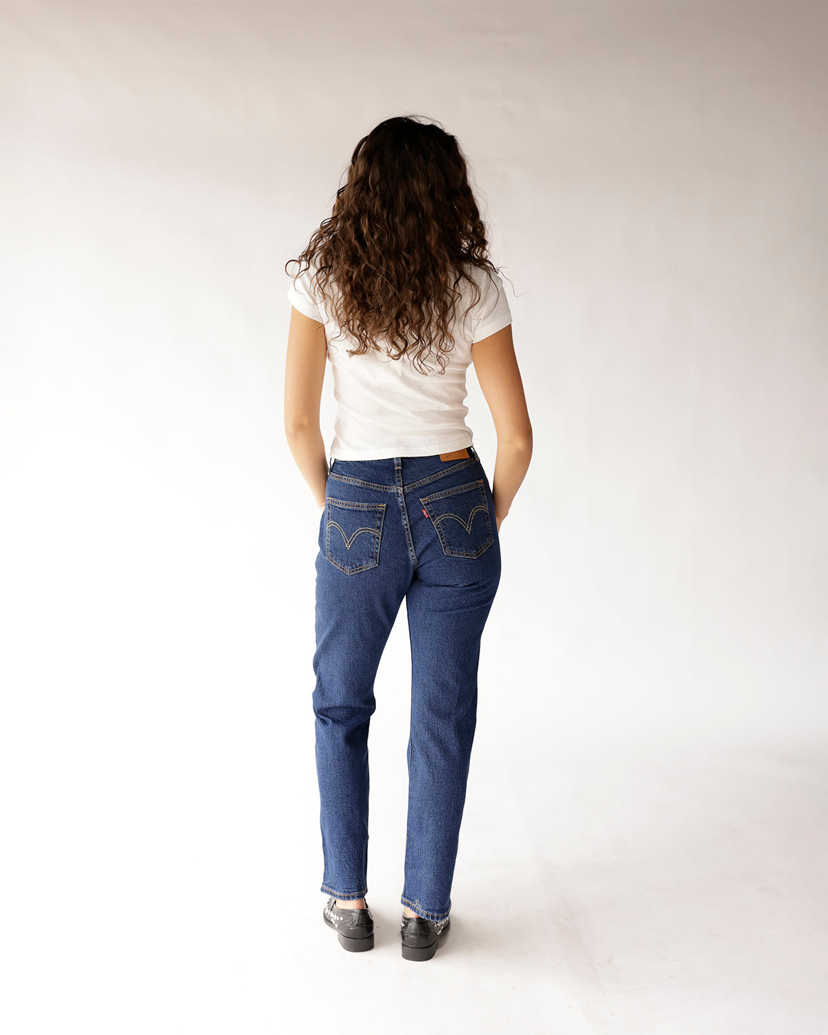Dark blue straight-leg denim jeans worn with white fitted tee, back view
