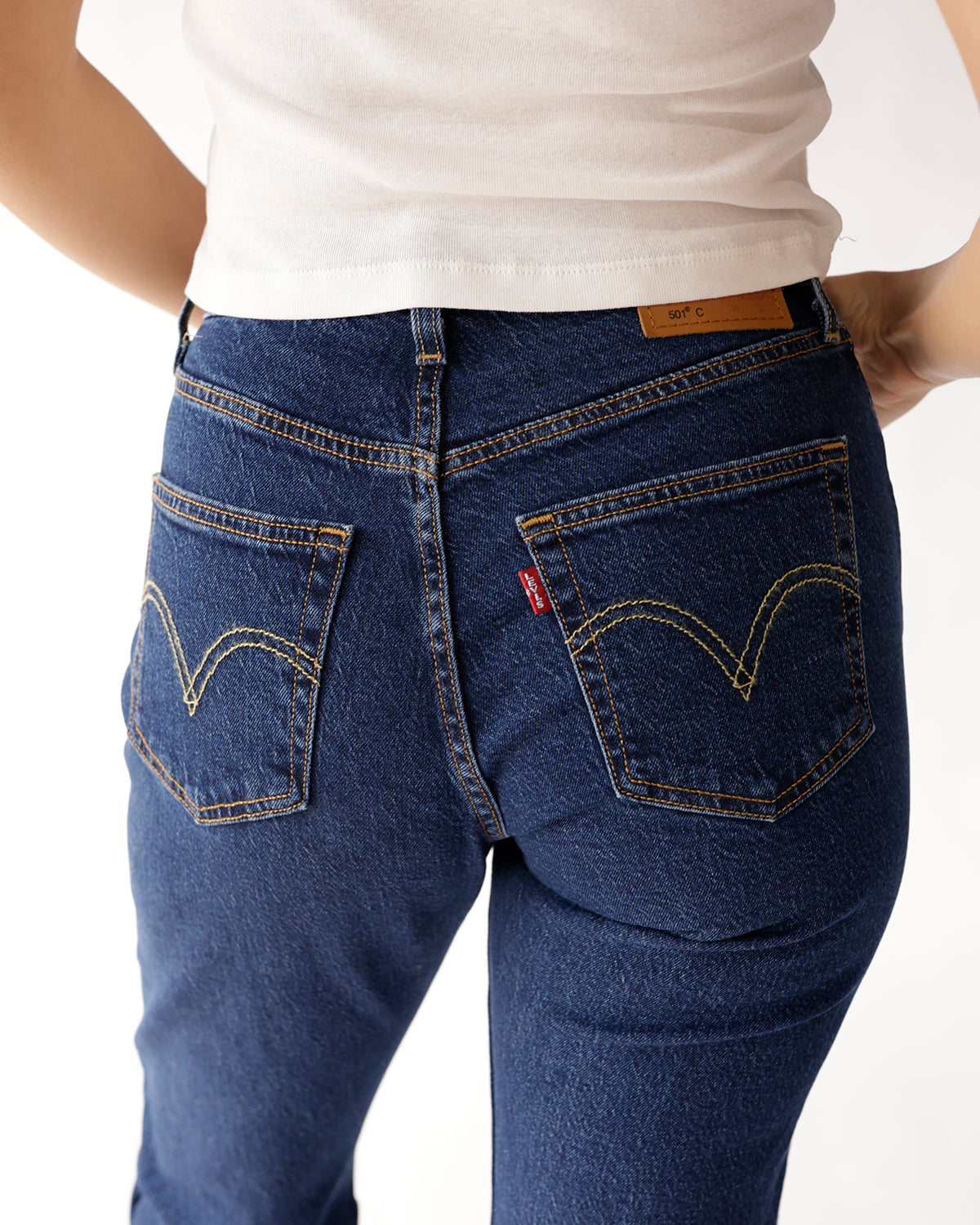 Back view of dark blue denim jeans with gold stitching and double back pockets