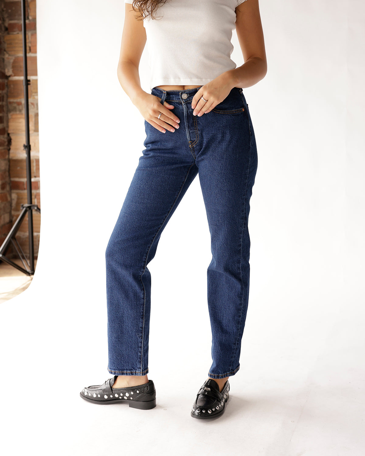 Dark blue high-rise straight-leg jeans styled with white crop top and black studded loafers
