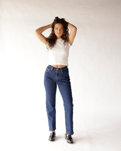Dark blue straight-leg jeans worn with white crop top and black loafers