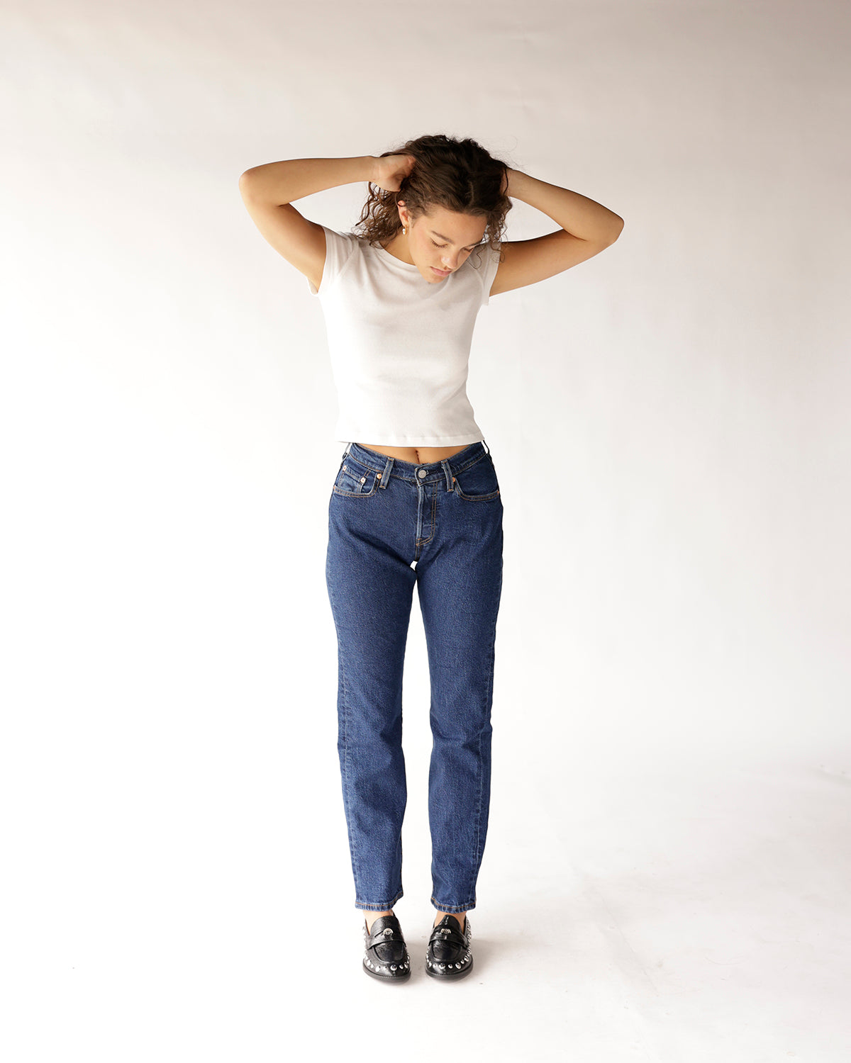 Dark blue straight-leg jeans with classic five-pocket styling, worn with white crop top