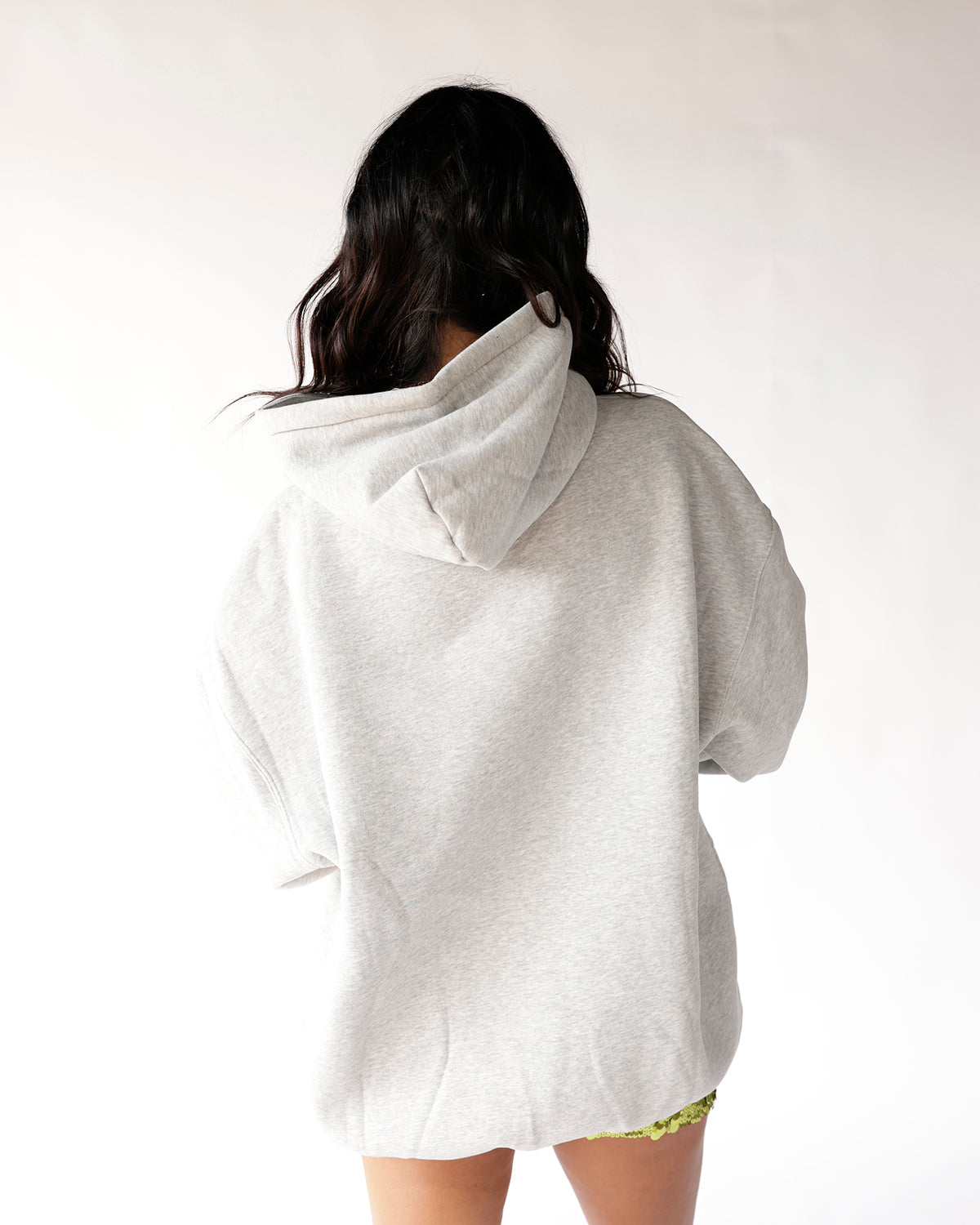 Oversized grey heather hoodie shown from the back, paired with green shorts.