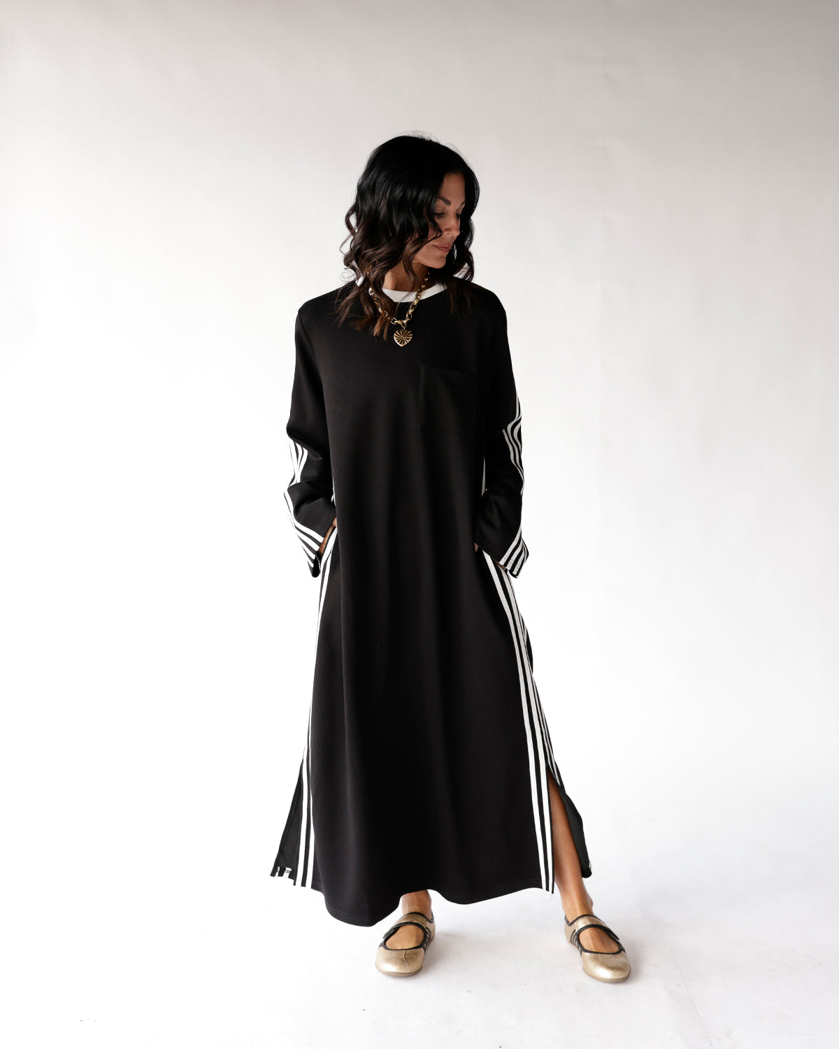 Black maxi dress with white side stripes, long sleeves, and side slit