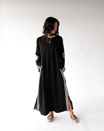 Black maxi dress with white side stripes, long sleeves, and side slit