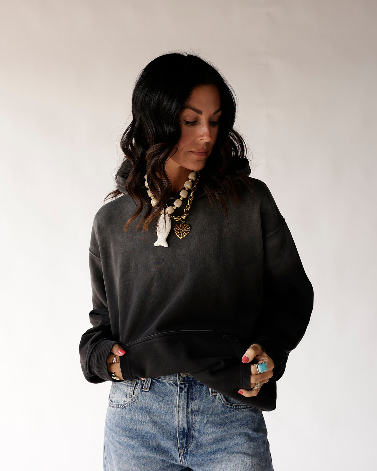Oversized black cropped hoodie sweatshirt styled with light wash jeans and layered necklaces
