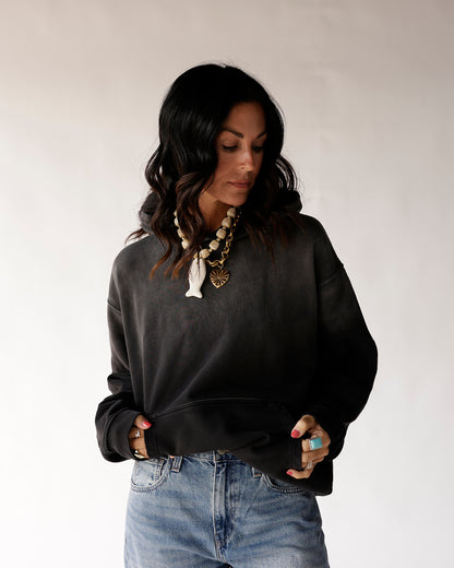 Oversized black cropped hoodie sweatshirt styled with light wash jeans and layered necklaces
