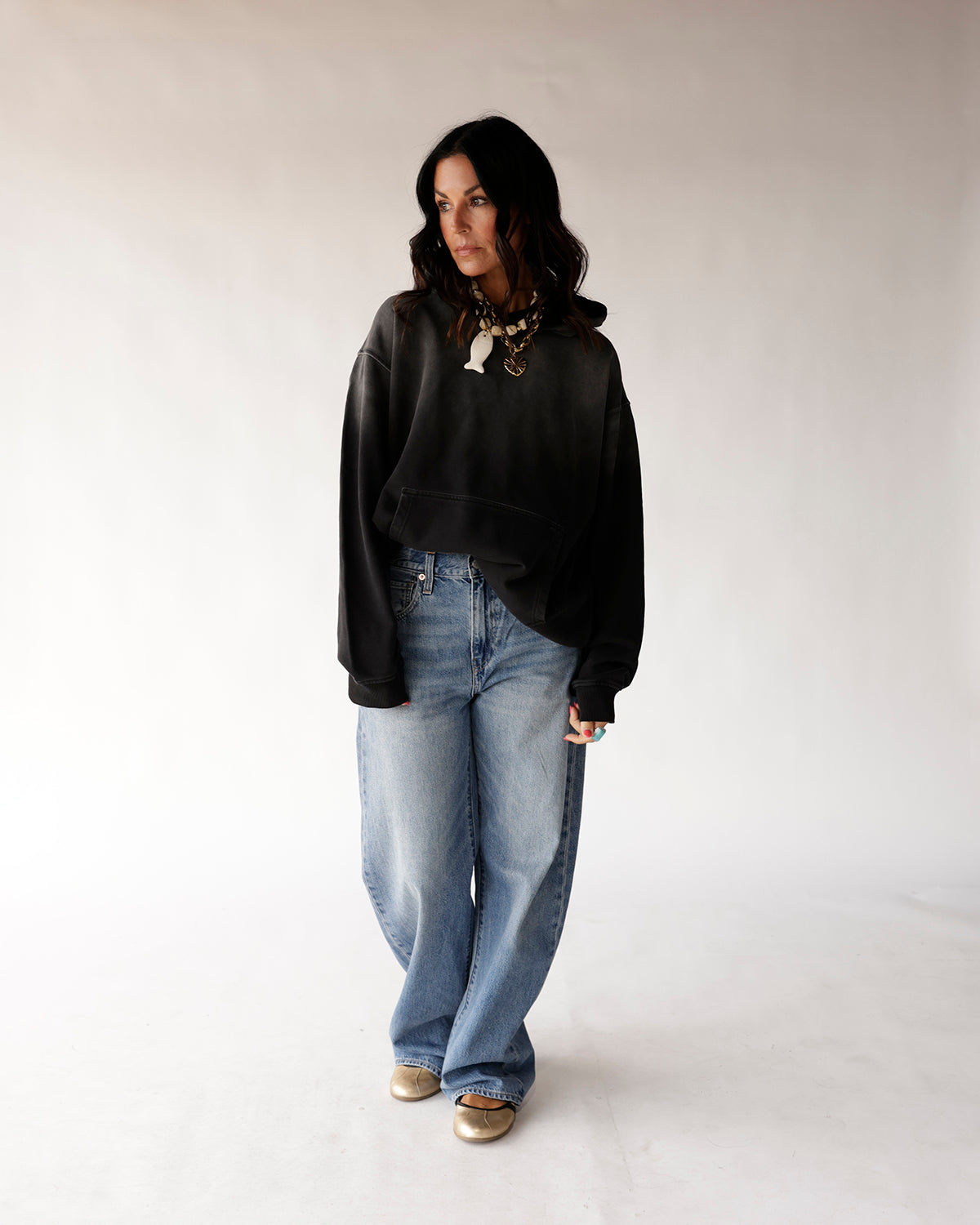 Oversized black washed hoodie with front pocket, worn with wide-leg jeans