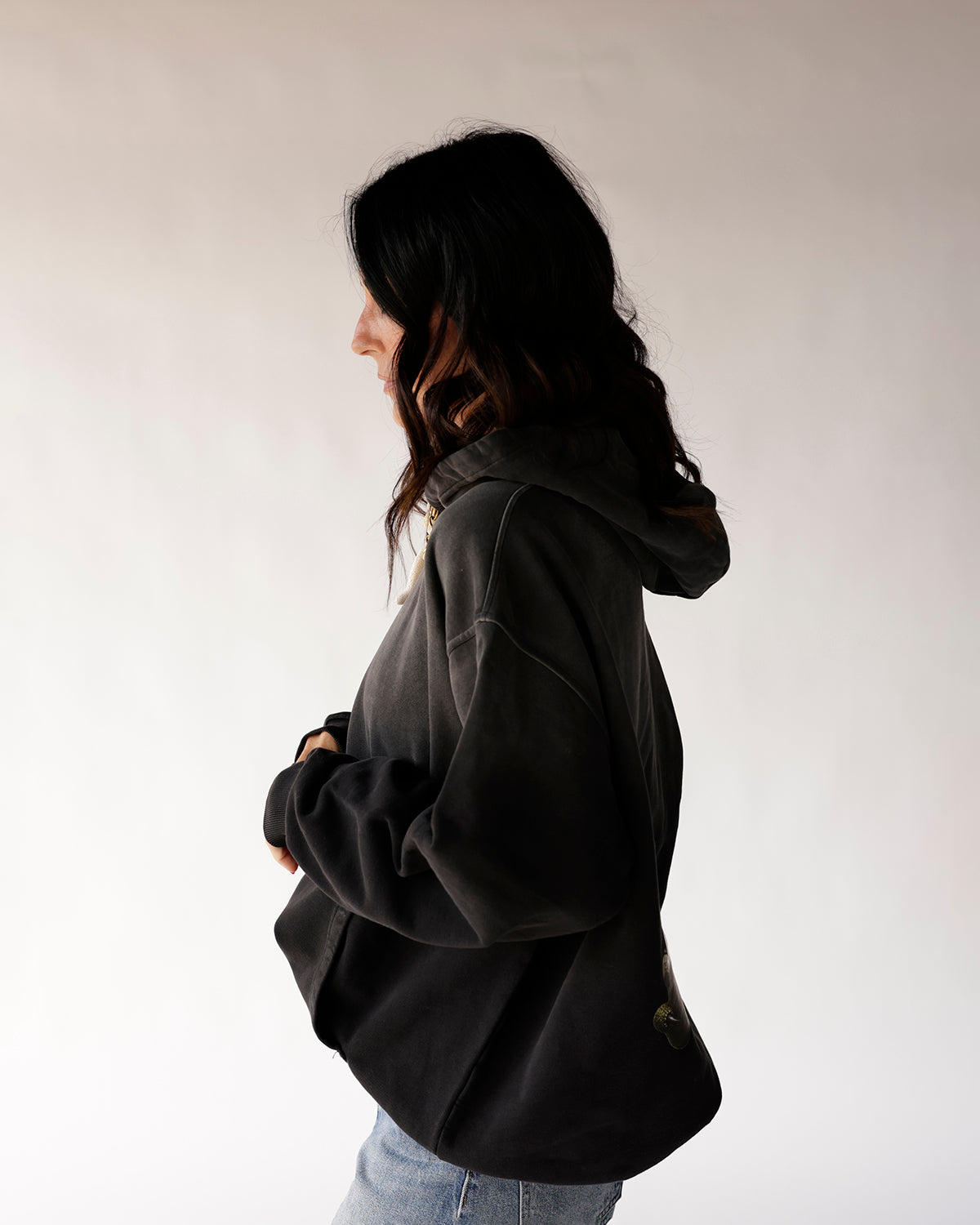 Oversized black hoodie side profile view, worn with blue jeans