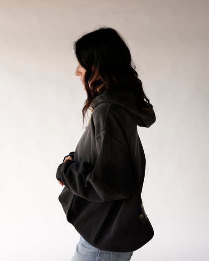Oversized black hoodie side profile view, worn with blue jeans