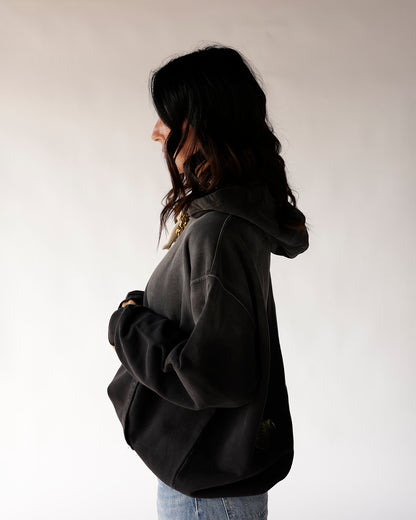 Oversized black washed hoodie with hood down, side profile view, relaxed fit