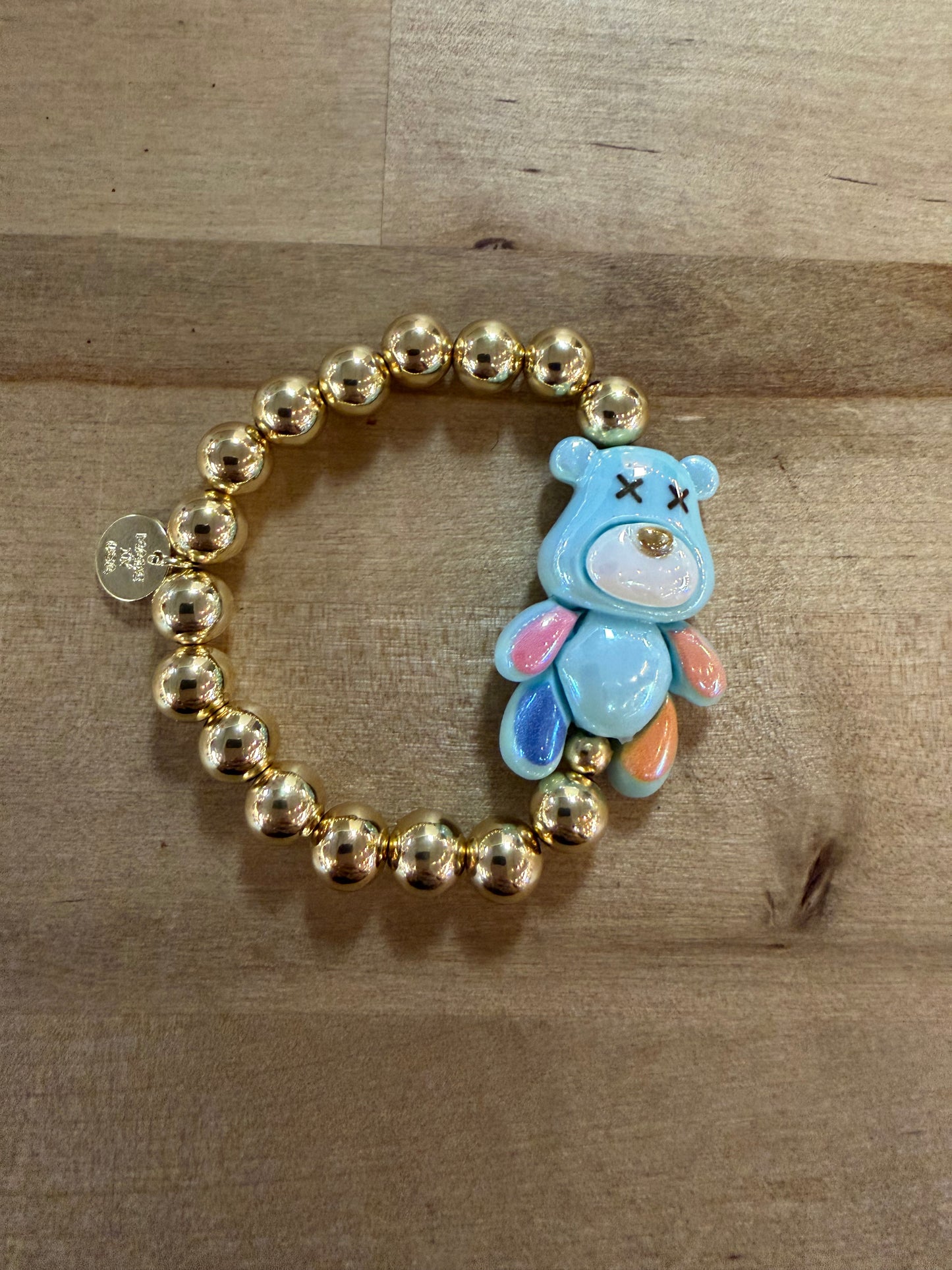 Gold beaded stretch bracelet with blue enamel bear charm featuring X eyes