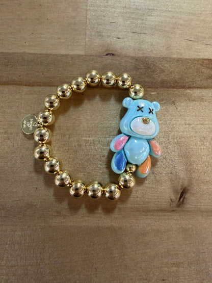 Gold beaded stretch bracelet with blue enamel bear charm featuring X eyes