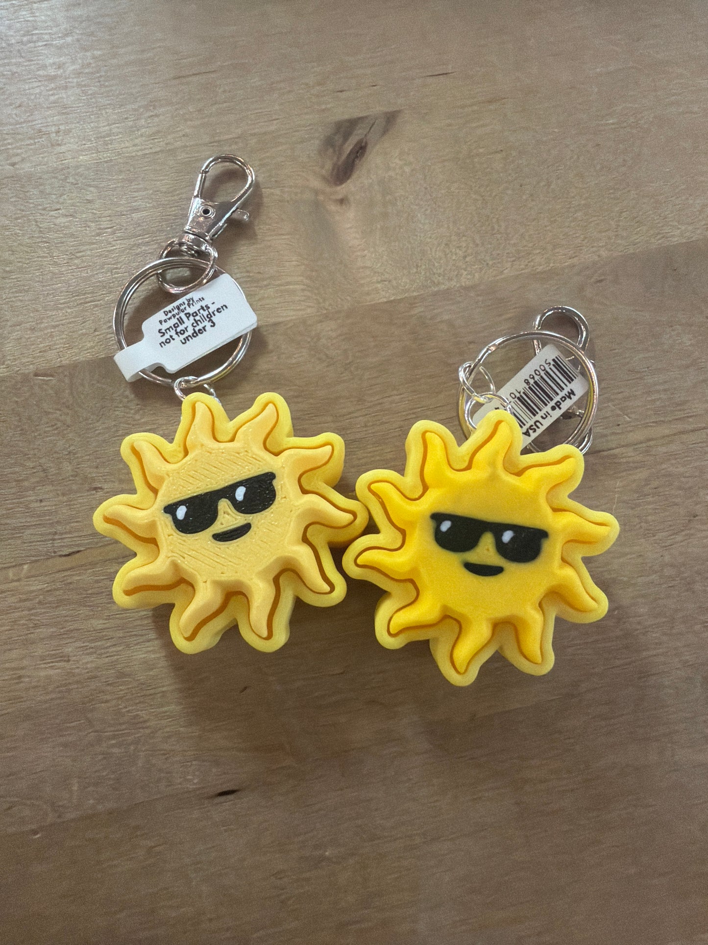 Two yellow sun with sunglasses keychains on silver lobster claw clasps