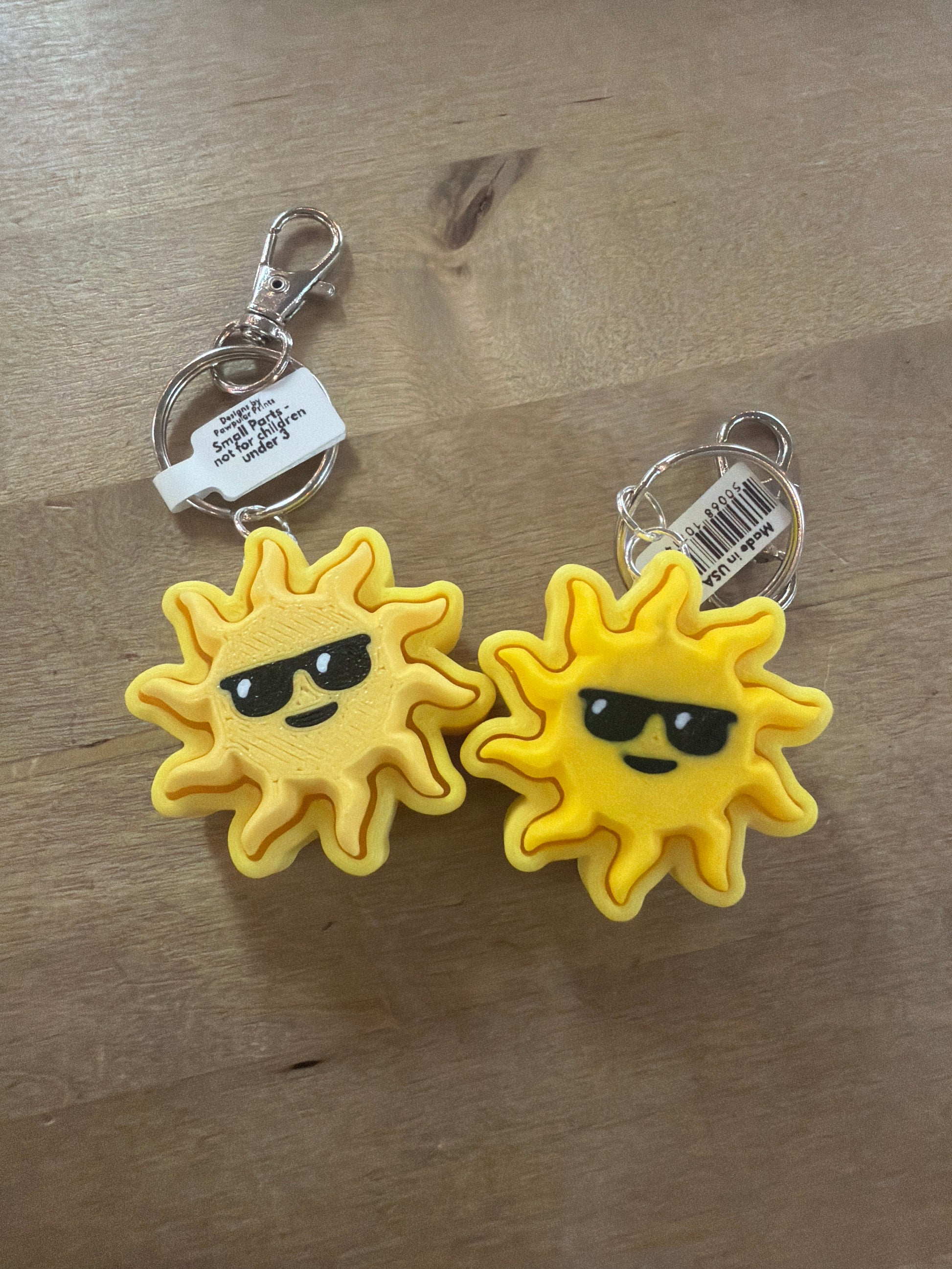 Two yellow sun with sunglasses keychains on silver lobster claw clasps