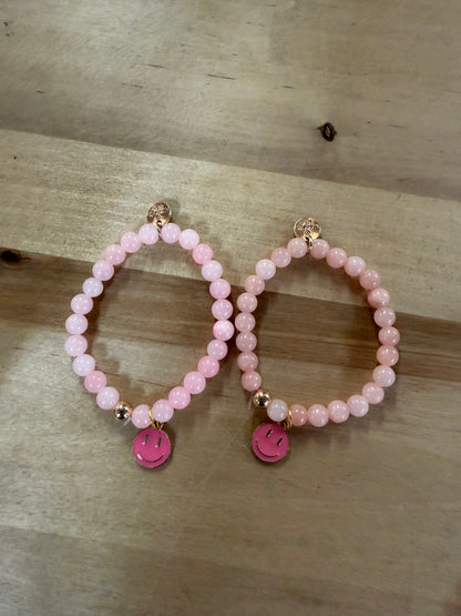 Two pink beaded stretch bracelets with hot pink enamel smiley face charms