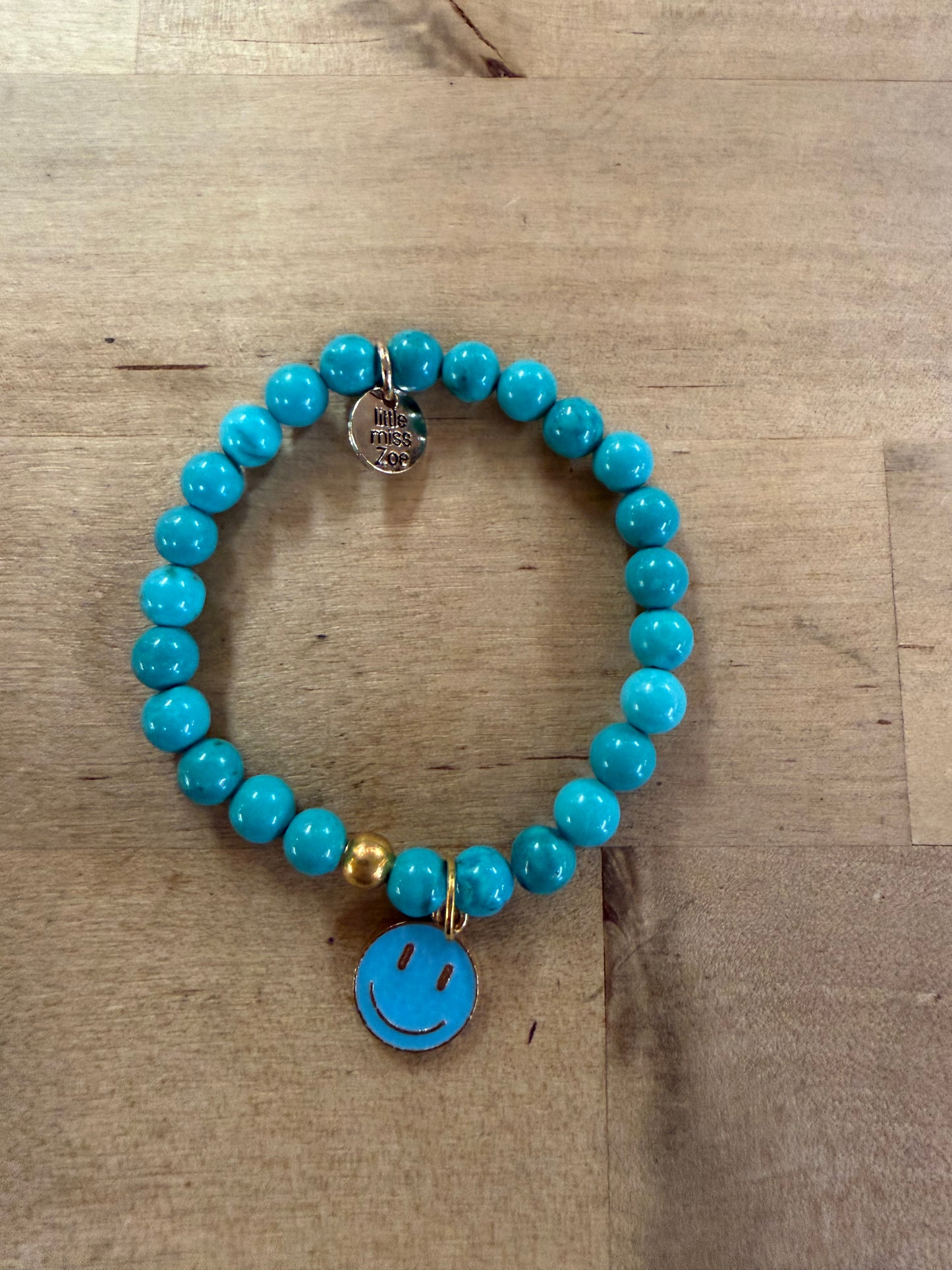 Turquoise beaded stretch bracelet with blue enamel smiley face charm and gold bead