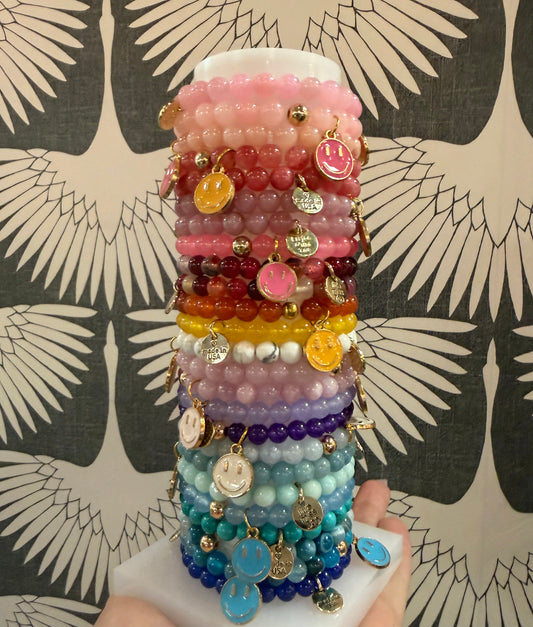 Girls’ smiley face beaded charm bracelets featuring colorful solid beads and a fun smiley face charm. Stretchy, playful, and perfect for gifting!
