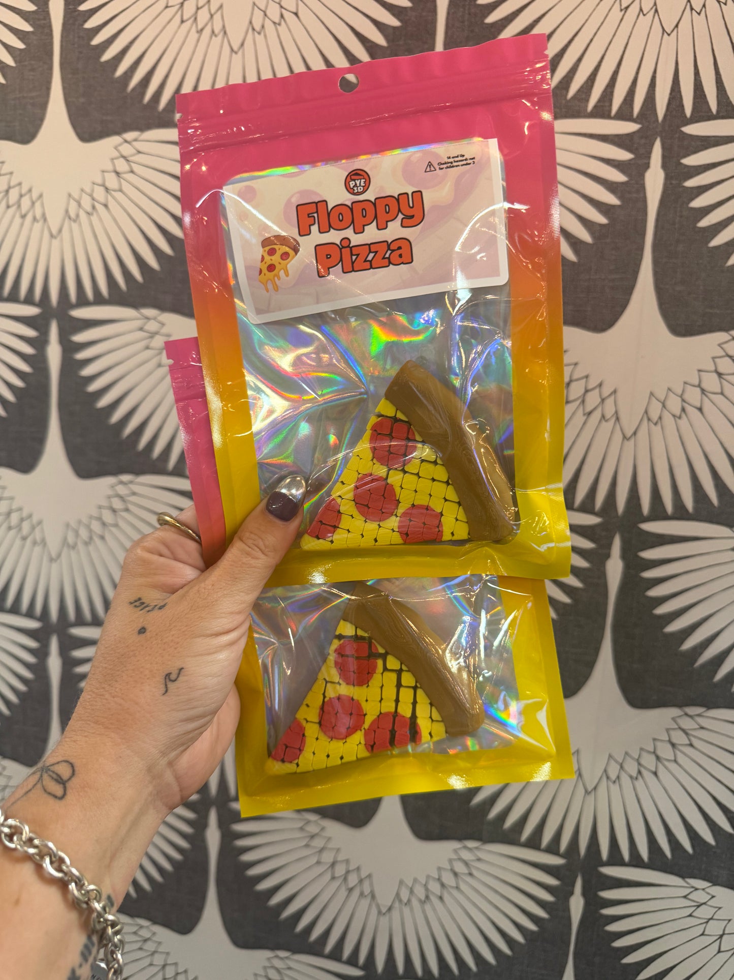 PYE Games Floppy Pizza fidget toy, two pizza slice shaped flexible toys in holographic packaging